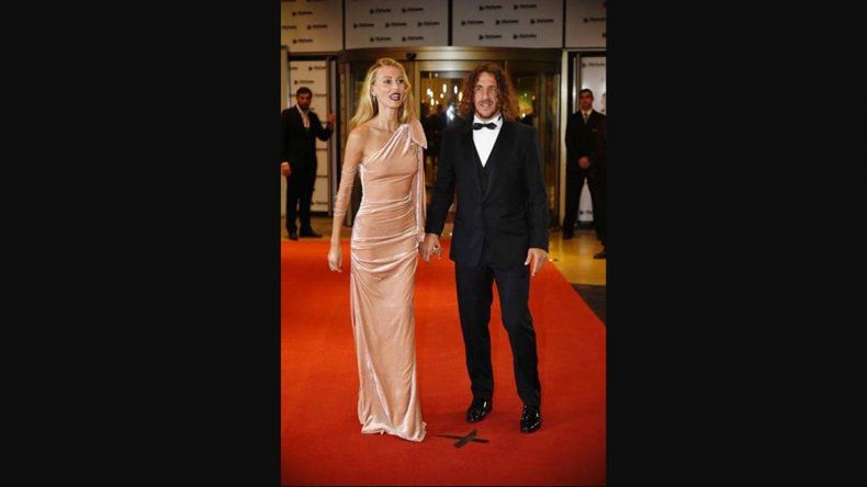 Carles Puyol y su mujer, Vanesa Lorenzo también posaron para la prensa. Puyol se inclinó por un smoking de corte clásico y sumó un chaleco al estilismo. Lorenzo deslumbró con un diseño largo en chifón, de un sólo hombro en color rosa pálido.