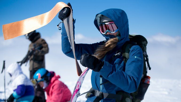 Jenny le pone las pieles artificiales de foca a las splitboards para poder trepar las laderas.