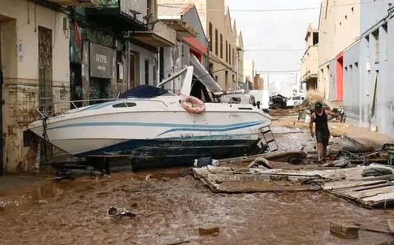 Calles cubiertas de barro con una embarcació arrastrada por la corriente Calles cubiertas de barro con una embarcació arrastrada por la corriente