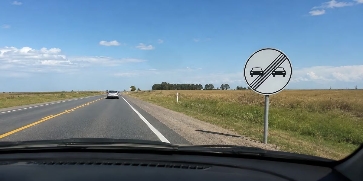 Qué significa la señal de tránsito con dos autos juntos en fondo blanco y cuatro líneas diagonales