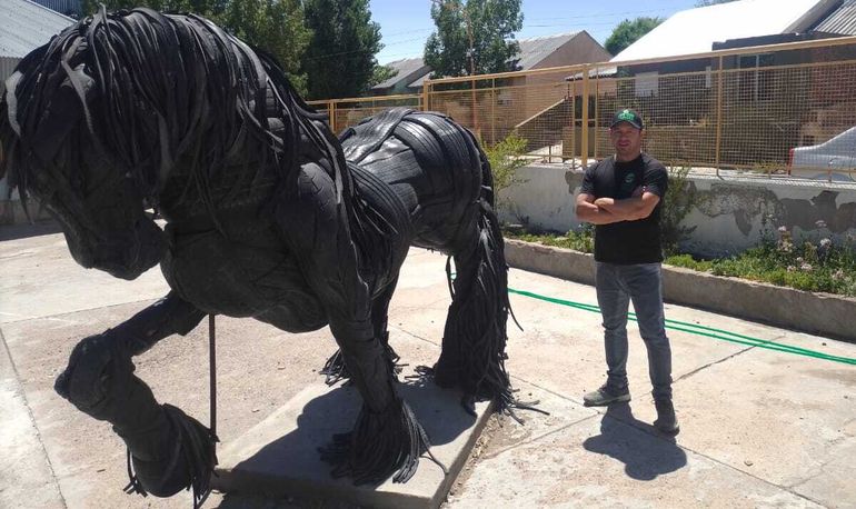 Cristian Méndez al lado de su obra de un caballo frisón en la Escuela de Arte N°1 de Zapala.&nbsp;
