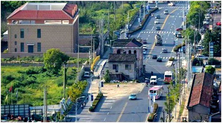 Una casa en medio de una gran avenida.