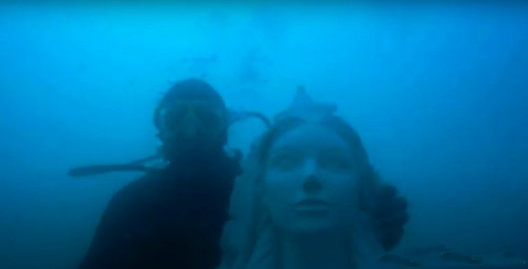 Un buzo junto a la estatua de la virgen Stella Maris, construida por la artista local Lidia Gómez.