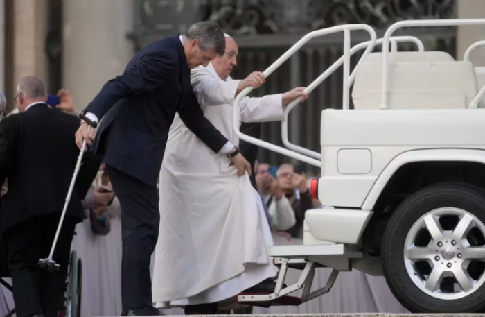 Un asistente ayuda al Papa en su intento por subir al papamovil.