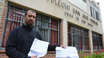 Gastón Maina, administrador del colegio, exhibe las boletas de servicios que se le hace muy difícil pagar.