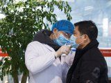 Un trabajador de salud toma la temperatura corporal a un hombre en la sala de embarques del aeropuerto de Changsha, en la provincia de Hunan, como medida de precaución debido al brote de coronavirus.