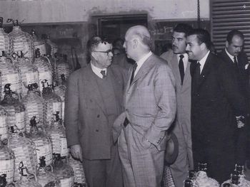 Visita del gobernador Castello en Cipolletti, año 1960. Visita a la Bodega Flor del Prado. En la imagen se ven las damajuanas de vino. Gentileza: Archivo Cabus Trenes