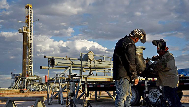 Dos trabajadores realizan una maniobra en la boca del pozo.
