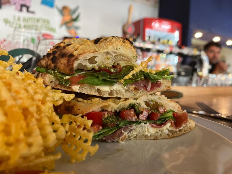 Rico sándwich de stracciatella, jamón crudo, pesto, rúcula, oliva y cherrys con papas rejillas en pan de pizza. Rico sándwich de stracciatella, jamón crudo, pesto, rúcula, oliva y cherrys con papas rejillas en pan de pizza.