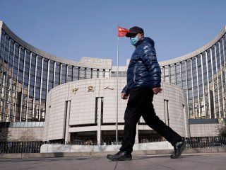 FOTO DE ARCHIVO. Un hombre con una mascarilla camina frente a la sede del Banco Popular de China, el banco central, en Pekín, China, mientras el país se ve afectado por un brote del nuevo coronavirus.