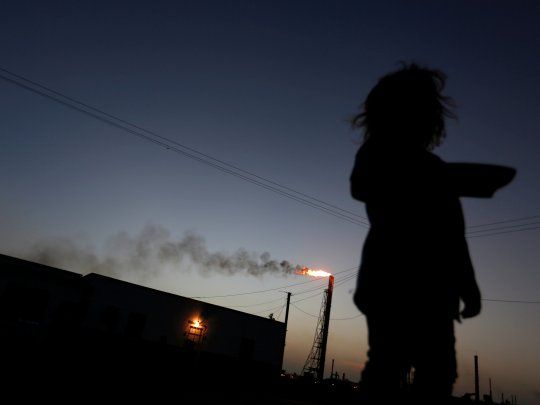 FOTO DE ARCHIVO: Una niña se para frente a su casa mientras la refinería Cardón, que pertenece a la petrolera estatal venezolana PDVSA, es vista al fondo, en Punto Fijo, Venezuela, foto tomada el 22