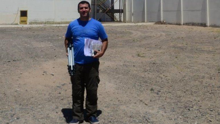 El periodista que investigó y descubrió a Wilson en la U11. De fondo la torre de vigilancia donde estuvo apostado por años el muñeco.