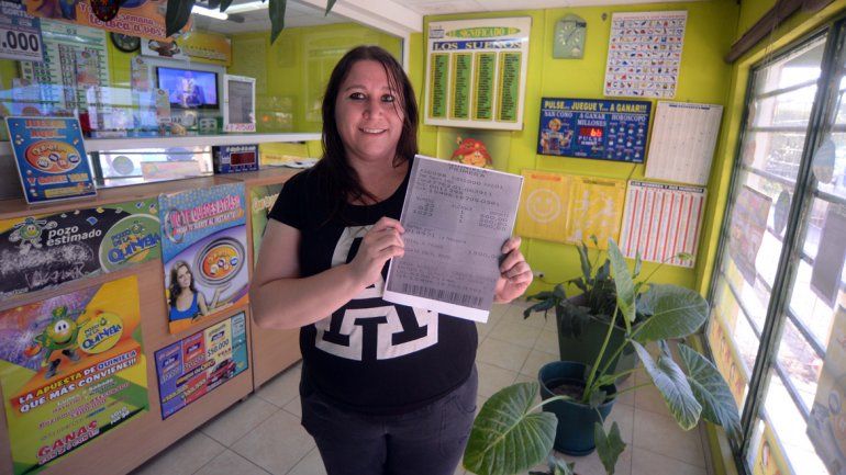 La agenciera exhibe los números ganadores de la Lotería La Neuquina.