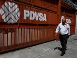 Foto de archivo. Un hombre pasa junto a un portón con el logo corporativo de la petrolera estatal PDVSA en Caracas, Venezuela, 3 de noviembre, 2017. REUTERS/Marco Bello