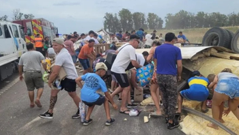 Mientras los socorristas trabajaban en sacar al chofer del camión, vecinos se llevaban la carga. Foto: La Opinión de Pergamino.