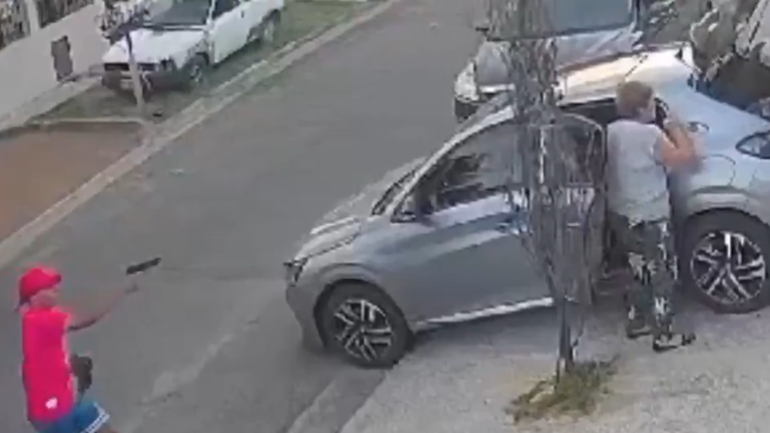 El delincuente armado en el momento que protgoniza el robo del auto