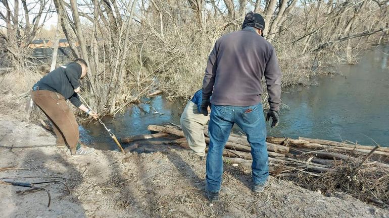 Vecinos y Defensa Civil comenzaron a quitar postes para arreglar un puente interno desbordado por el brazo del río.