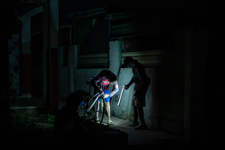 Dos personas se iluminan durante el apagón nacional del 21 de marzo en La Habana. Foto: El País. Dos personas se iluminan durante el apagón nacional del 21 de marzo en La Habana. Foto: El País.