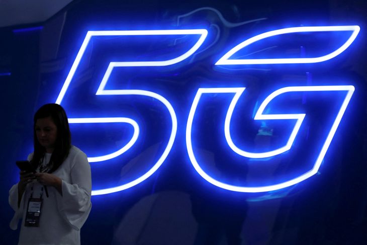 FOTO DE ARCHIVO: Una mujer mira su teléfono móvil junto a una señal luminosa de 5G en el Mobile World Congress en Barcelona, España, el 25 de febrero de 2019. REUTERS/Sergio Pérez
