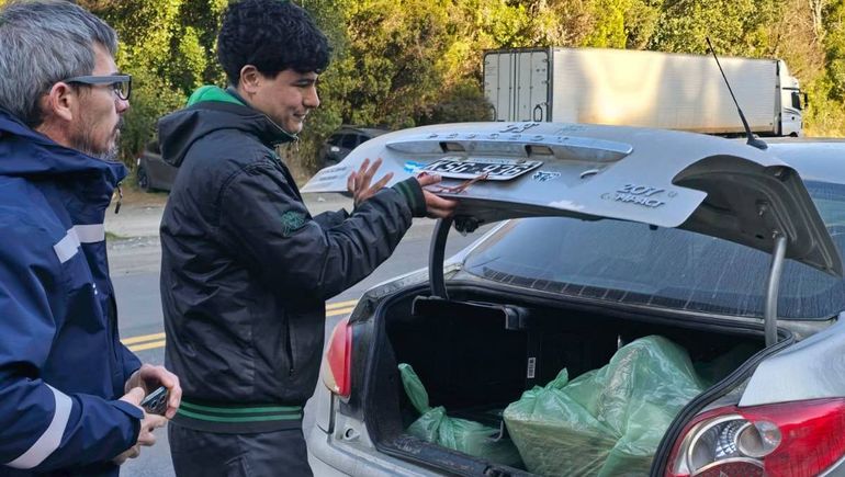 Los inspectores en el decomiso de la mercadería en el baúl de un auto.