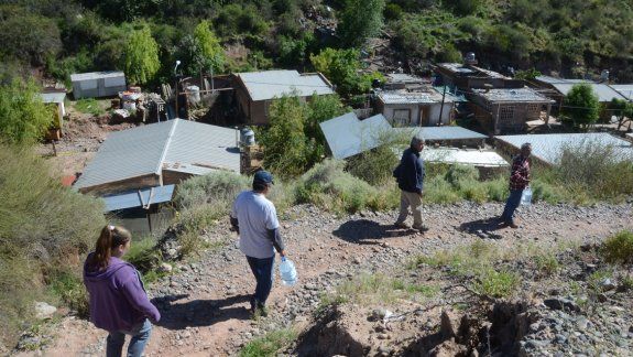 Los vecinos volvieron ayer al barrio, ubicado en un cañadón (una parte), con bidones de agua potable.