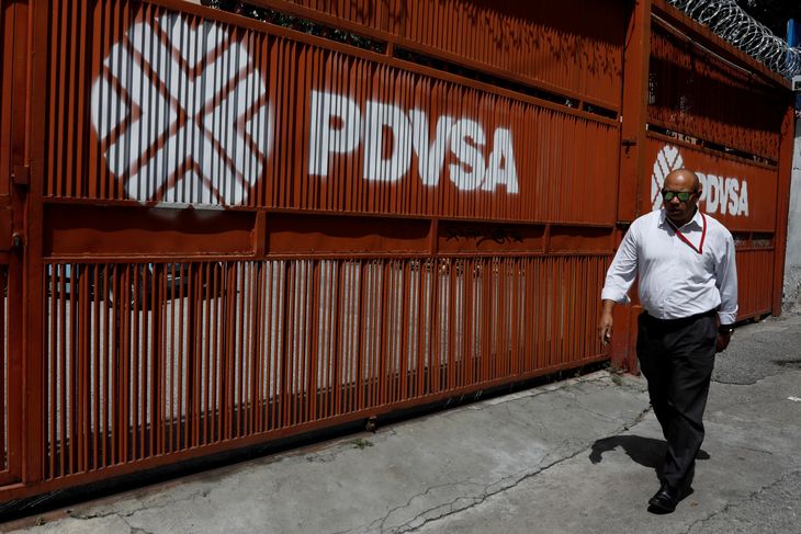 Foto de archivo. Un hombre pasa junto a un portón con el logo corporativo de la petrolera estatal PDVSA en Caracas