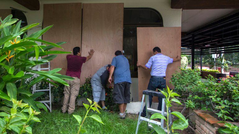 Cuatro hombres colocando protecciones para mitigar el impacto del potente huracán.