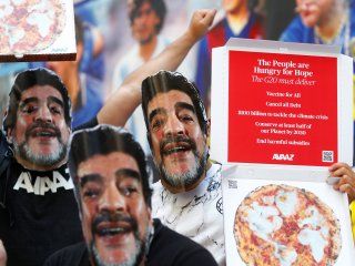 Activistas del grupo Avaaz, con máscaras que representan al fallecido jugador de fútbol argentino Diego Armando Maradona, organizan una protesta pidiendo un alivio de la deuda por el clima mientras