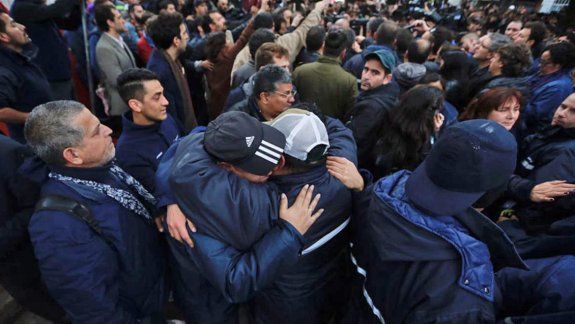 Dos trabajadores de Pepsico se abrazan tras el violento desalojo.