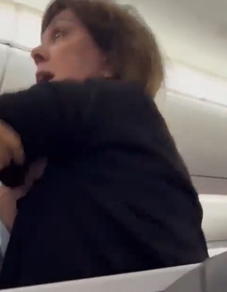 La mujer siendo trasladada a su asiento tras agredir al piloto. La mujer siendo trasladada a su asiento tras agredir al piloto.