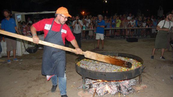 Al calor de las brasas, Donato revuelve muy despacio el arroz con mariscos que preparó para 500 comensales.