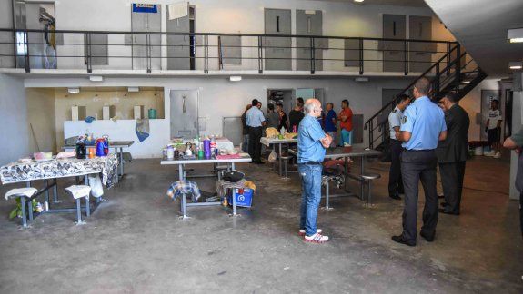 El ingreso al anexo penal de Senillosa que tiene la U9. Los presos, en el salón de usos múltiples donde conviven gran parte del día. En uno de los talleres fabrican cepillos para su futura venta.