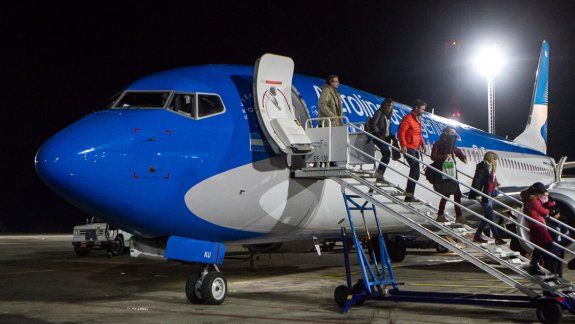 Los pasajeros del primer vuelo nocturno a Chapelco descienden felices en la pista recién iluminada.