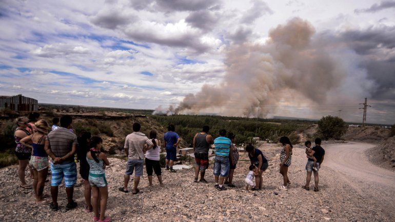 Curiosos miran la columna de fuego en Nueva España mientras los bomberos combaten el fuego.