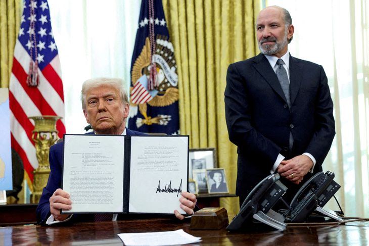 FOTO DE ARCHIVO. El presidente de Estados Unidos, Donald Trump, sostiene una orden ejecutiva sobre el aumento de aranceles, flanqueado por el secretario de Comercio, Howard Lutnick, en la Oficina Oval