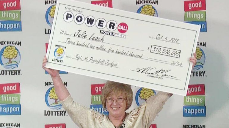 Julie Leach alzando el cheque que la acredita como dueña de su nueva fortuna.