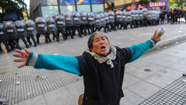 La mujer se arrodilla entre la Policía y los manifestantes