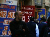 Foto de Archivo: La gente pasa cerca de los paneles que muestran el tipo de cambio del dólar estadounidense y otras divisas frente al peso chileno en una oficina de cambio de moneda en el centro de