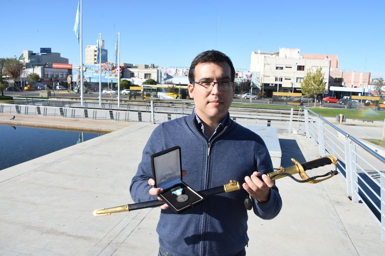 Mario Flores Monje con el sable de su padre, que murió en el hundimiento del crucero General Belgrano, y una medalla.